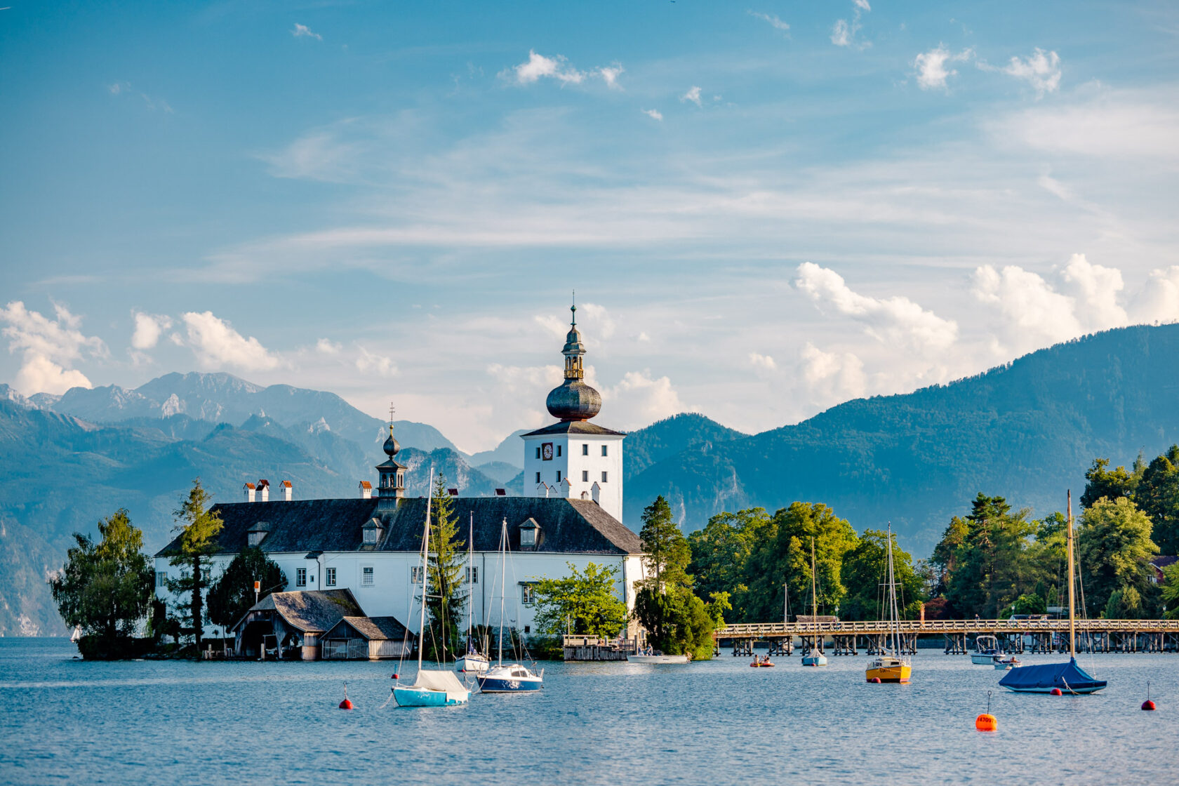 Historisches Gebäude am See mit Segelbooten und Bergen im Hintergrund in der kleinen historischen Stadt Gmunden.